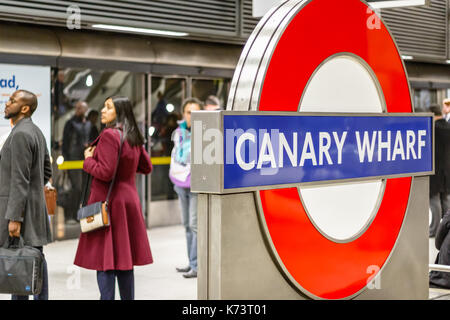 London, Großbritannien - 15 September, 2017 - Canary Wharf U-Schild mit pendler Warten auf einer Plattform im Hintergrund Stockfoto