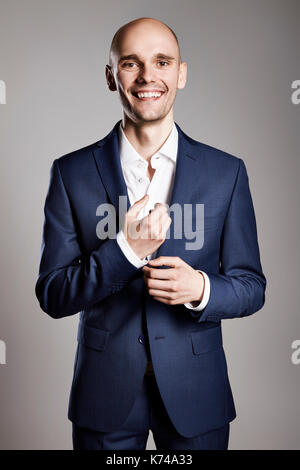 Junge lächelnde Geschäftsmann zur Festsetzung Manschettenknöpfe seinen Anzug. Stockfoto