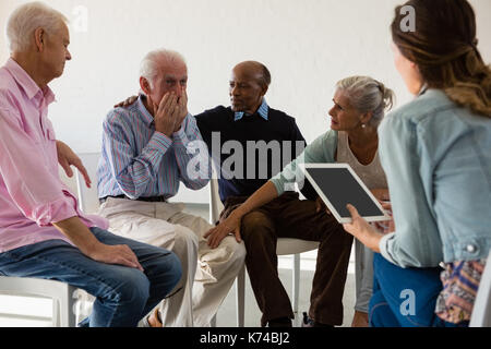 Ältere Freunde tröstende Mann während der Diskussion im Kunstunterricht Stockfoto