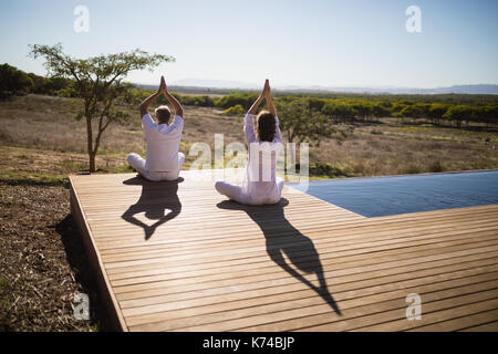 Ansicht der Rückseite des paar Üben Yoga auf Holzbrett an einem sonnigen Tag Stockfoto