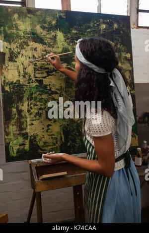 Aufmerksame Frau Malerei auf Leinwand in Zeichnung Klasse Stockfoto