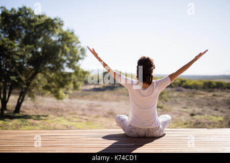 Praktizierende frau yoga auf Holzbrett an einem sonnigen Tag Stockfoto