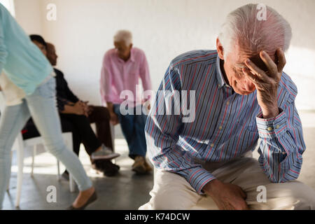 Angespannt älterer Mann mit Freunden im Hintergrund in der Kunst Klasse Stockfoto
