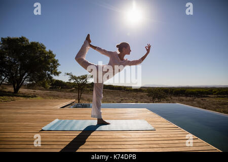 Frau Yoga auf am Pool an einem sonnigen Tag Stockfoto