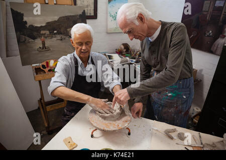 Aufmerksame ältere Menschen Unterstützung bei Töpfern beim Zeichnen Klasse Stockfoto