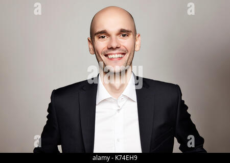 Studio erschossen der junge Mann in die Kamera schaut. Horizontales Format, er lächelt, er trägt einen schwarzen Jacke. Stockfoto