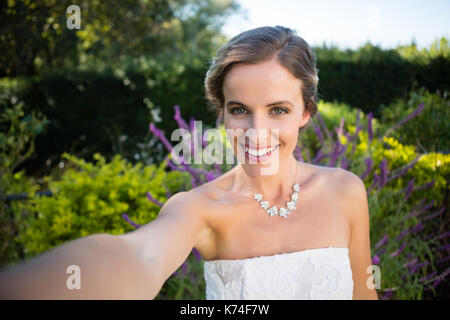 Portrait von lächelnden schöne Braut sich gegen Pflanzen im Hof Stockfoto