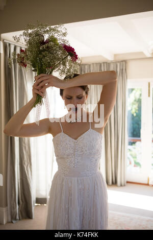 Wütende Braut werfen Blumenstrauß während zu Hause stehend Stockfoto