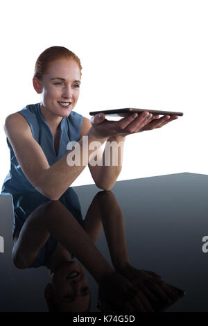 Lächelnden jungen Geschäftsfrau Holding digital Tablet am Tisch vor weißem Hintergrund Stockfoto