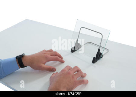 7/8 Hände der Geschäftsmann Tippen auf imaginäre Tastatur, während die Verwendung von Glas Schnittstelle am Tisch vor weißem Hintergrund Stockfoto