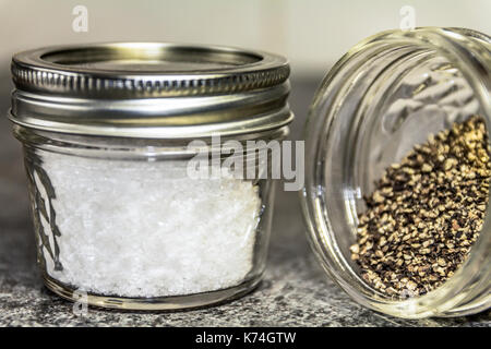 Meersalz und schwarzer Pfeffer in kleinen Gläsern Stockfoto