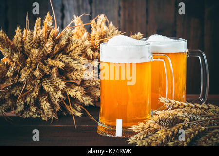 Zwei Gläser helles Bier mit ährchen von Gerste auf dem hölzernen Hintergrund. Schönen Hintergrund des Oktoberfestes Stockfoto