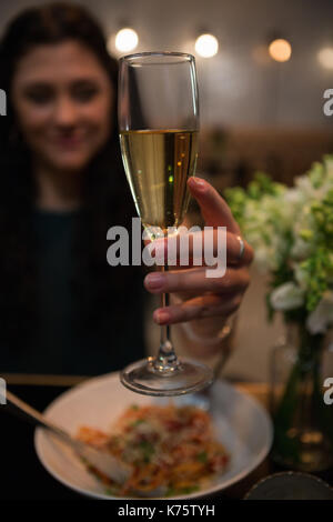Frau mit Champagner beim Essen im Restaurant Stockfoto