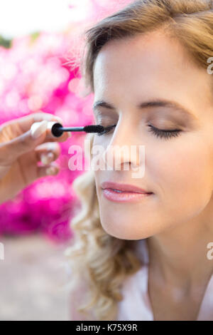 7/8 Hand von Frau Anwendung Mascara zu Braut im Hof Stockfoto