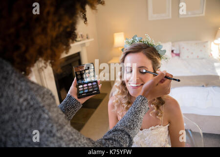 Frau Anwendung Make-up, glückliche Braut im Ankleidezimmer Stockfoto