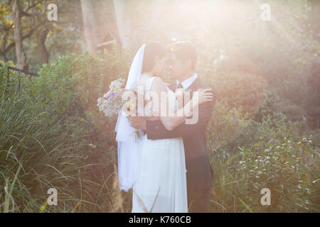 Romantische jungvermählte Paar mit geschlossenen Augen umarmt, während in PARK-Stellung Stockfoto