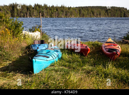 Rot, Orange, Blau Kajaks vor einem See an einem heißen Sommertag Stockfoto