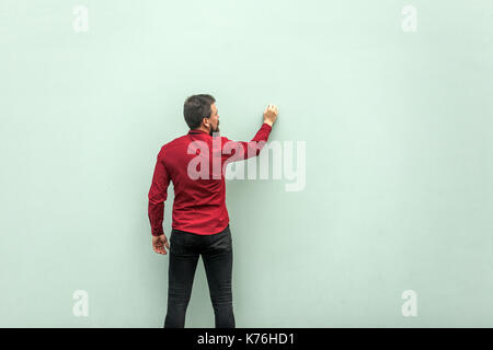 Junge Erwachsene Geschäftsmann Malerei auf graue Wand. Studio shot Stockfoto