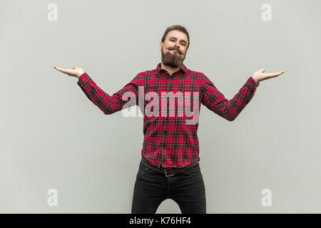 Ich weiß es nicht. Gutaussehender Geschäftsmann mit Bart und Schnurrbart, der Kamera anschaut und verwirrt ist. studioaufnahme, auf grauem Hintergrund. Stockfoto