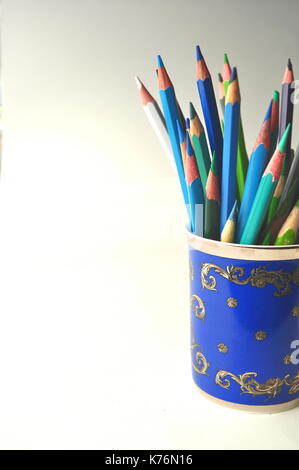 Blau Porzellan Tasse mit blau Bleistifte, offenes Buch und leerer Hinweis Karte auf blauen und weißen Hintergrund - flach gestaltete legen Stockfoto