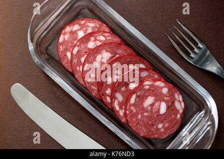Scheiben Salami auf einem Teller mit Besteck Stockfoto