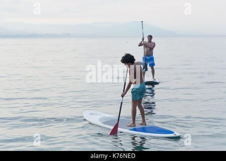 Junge und weiter üben bis Paddles stand mit Bergen im Hintergrund verschwommen Stockfoto