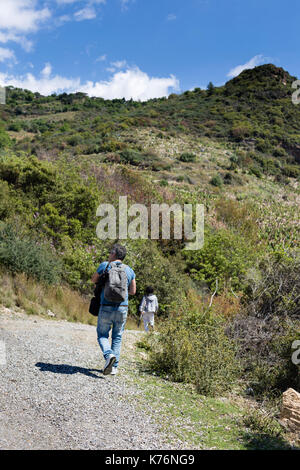 Touristische Mann in Jeans und Sport shoos und grau Rucksack und junge tragen graue Kleidung Trekking im mediterranen Berge von Evergreen Plan abgedeckt Stockfoto