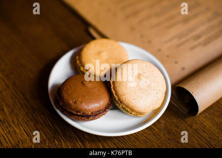 Die leckeren Macarons mit Schokolade, Kaffee und Cappuccino schmeckt am Hintergrund des CRAFT-Menü. Stockfoto