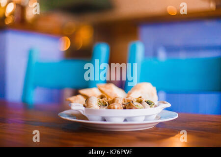 Die Seitenansicht der Platte voll von schneckengehäusen voller Kaviar Im verschwommenen Hintergrund des Restaurants. Stockfoto