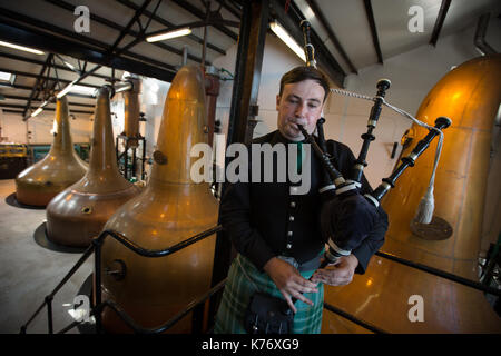 Bowmore Whisky Distillery mit Dudelsackspieler, Bowmore, in Schottland, am 15. September 2017. Stockfoto