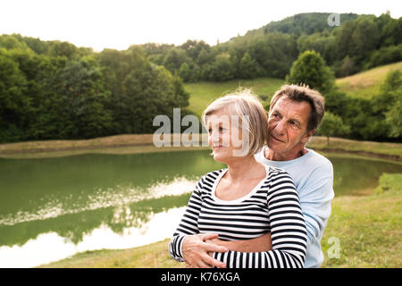 Senior Paar auf einem Spaziergang am See umarmen. Stockfoto