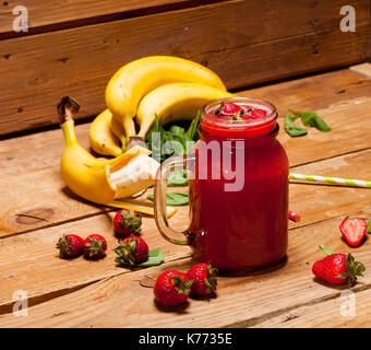 Erdbeeren und Bananen Smoothie oder Milchshake in einem Glas und auf Holz- Hintergrund, gesunde Lebensmittel für Frühstück und Snacks Stockfoto