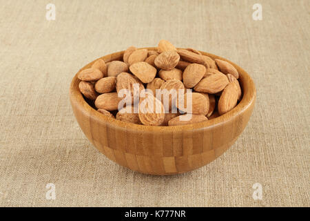 Gesalzene Mandeln in Bambusschüssel auf groben Leinentuch groß geschält Stockfoto