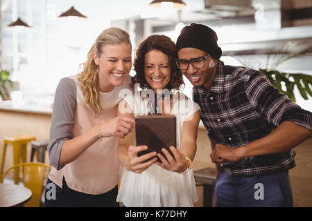 Fröhliche multi-ethnische Freunde unter selfie aus digitalen Tablet während Coffee Shop Stand Stockfoto