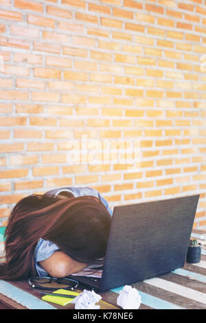 Nahaufnahme der jungen Frauen Business ist Gefühl Belastung mit ihr Arbeiten am Schreibtisch. geringe Tiefenschärfe, selektiver Fokus auf Kopf. vintage Tone, Sonnenlicht eff Stockfoto