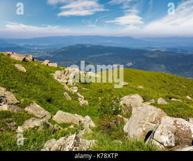 Riesige Felsbrocken auf einem grasigen Hang in den Bergen. schöne Berglandschaft mit Himmel voller Wolken Stockfoto