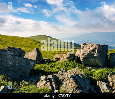 Riesige Felsbrocken auf einem grasbewachsenen Hügel bei Sonnenaufgang. wunderschöne Berglandschaft mit schönen Himmel Stockfoto