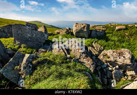 Riesige Felsbrocken auf einem grasbewachsenen Hügel bei Sonnenaufgang. wunderschöne Berglandschaft mit schönen Himmel Stockfoto