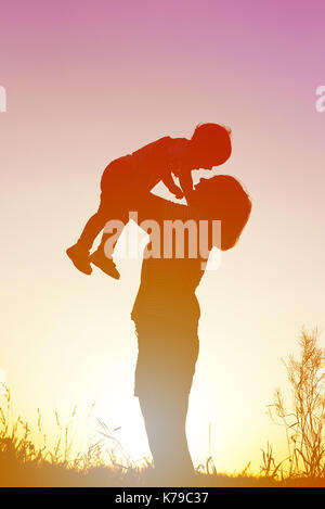 Silhouette einer Frau mit ihrem Kind bei Sonnenuntergang. Stockfoto