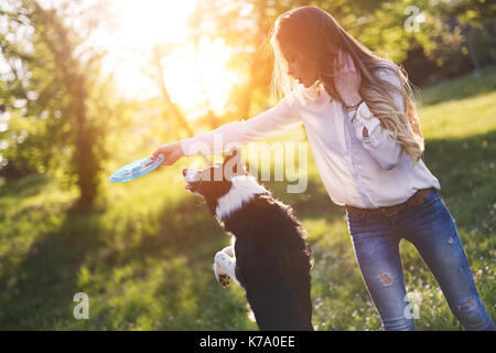 Schöne brünette Spielen mit Hund in der Natur bei Sonnenuntergang Stockfoto