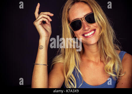 Junge Frau eine Sonnenbrille trug, fröhlich lächelnd, Porträt Stockfoto