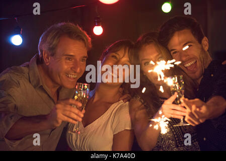 Freunde feiern mit Sekt und Wunderkerzen bei Party Stockfoto