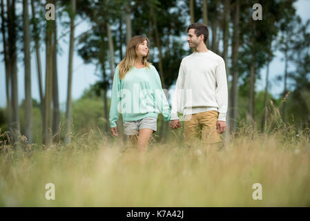 Junge Paare Hand in Hand durch hohes Gras Stockfoto