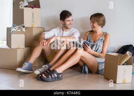 Junges Paar im neuen Haus sitzt mit Kartons Stockfoto