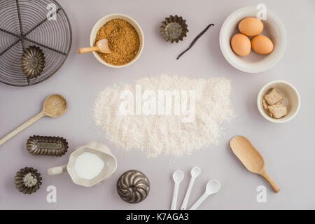 Flatlay Sammlung von Tools und Zutaten für zu Hause Backen auf hellgrauem Hintergrund mit Mehl copyspace in der Mitte geschossen von oben Stockfoto