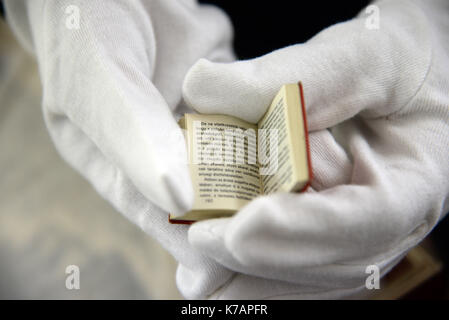 Trier, Deutschland. 15 Sep, 2017. Ein Mitarbeiter des Staatlichen Museums Holding die kleinste Version des "Kommunistischen Manifest" (Budapest, Ungarn, 1971) in Trier, Deutschland, 15. September 2017. 247 internationale Kredite des "Kommunistischen Manifest" von Karl Marx wurden dem Museum geliefert. Eine Ausstellung ist auf Anzeige anlässlich der 200. Geburtstag von Karl Marx in seinem Geburtsort vom 5. Mai bis 21. Oktober 2018. Foto: Harald Tittel/dpa/Alamy leben Nachrichten Stockfoto