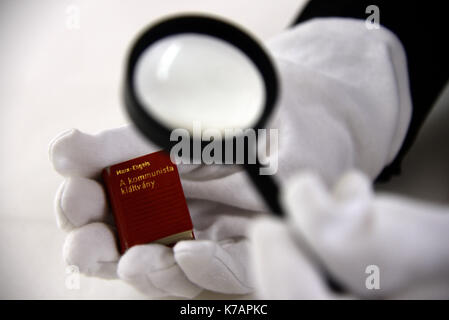 Trier, Deutschland. 15 Sep, 2017. Ein Mitarbeiter des Staatlichen Museums Holding die kleinste Version des "Kommunistischen Manifest" (Budapest, Ungarn, 1971) in Trier, Deutschland, 15. September 2017. 247 internationale Kredite des "Kommunistischen Manifest" von Karl Marx wurden dem Museum geliefert. Eine Ausstellung ist auf Anzeige anlässlich der 200. Geburtstag von Karl Marx in seinem Geburtsort vom 5. Mai bis 21. Oktober 2018. Foto: Harald Tittel/dpa/Alamy leben Nachrichten Stockfoto