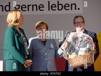 Trier, Deutschland. September 2017. CDU-Parteimitglied Bernhard Kaster (R) überreicht Bundeskanzlerin Angela Merkel (C) einen Geschenkkorb, wie die CDU-Parteivorsitzende Julia Kloeckner (L) in Rheinland-Pfalz bei einem Wahlkampfevent der CDU vor der Porta Nigra anschaut, Ein römisches Stadttor in Trier, Deutschland, 15. September 2017. Foto: Harald Tittel/dpa/Alamy Live News Stockfoto