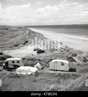 1950, historische, Wohnmobil, Wohnwagen und ein kleines Zelt aufgeschlagen auf Sanddünen auf einem schönen Küstenabschnitt mit einem langen Sandstrand, Nordirland, Großbritannien. Stockfoto