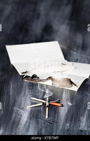 Rauchen und gebrannte spiele mit einer gebrannten Brief gegen eine dunkle grunge Hintergrund. Stockfoto